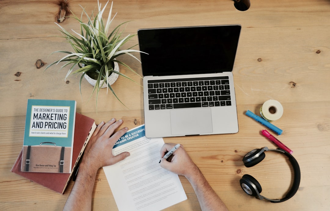 Marketing workspace flatlay with laptop, notebook, marketing books and headphones on a wooden desk — conversion copywriting planning setup. Photo by Unsplash.