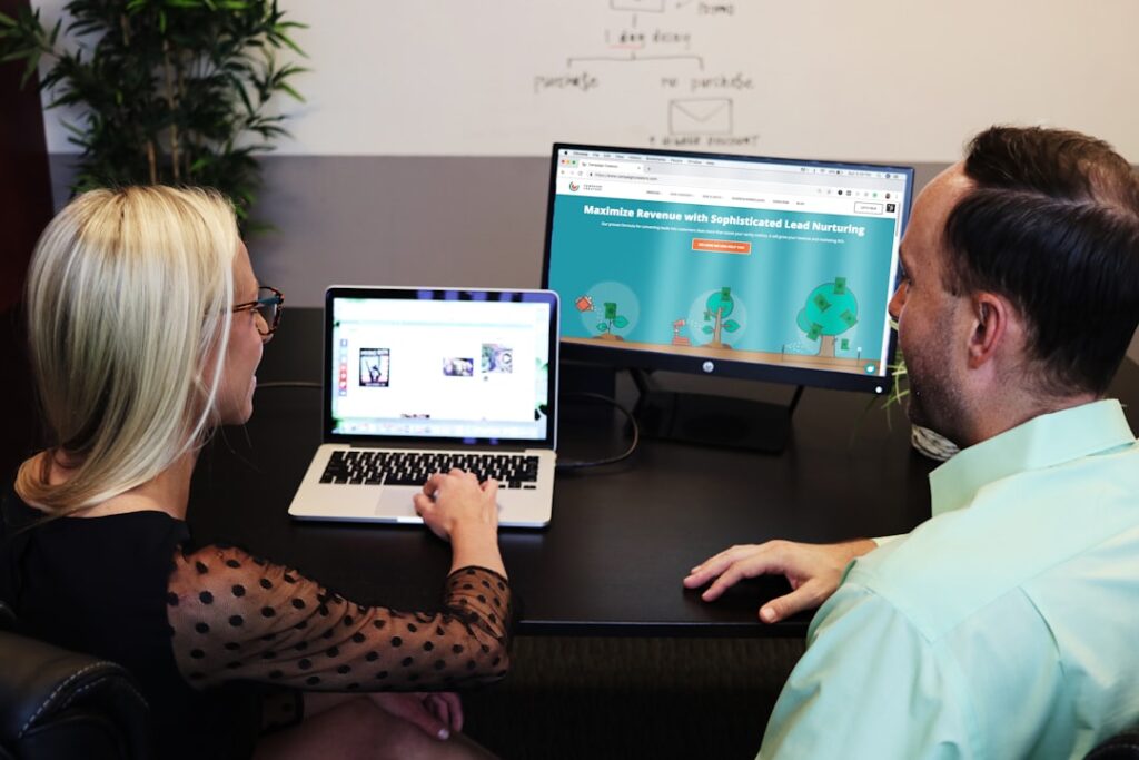 Two marketing professionals reviewing a live landing page on a large monitor, auditing design and copy choices that affect conversion rate.