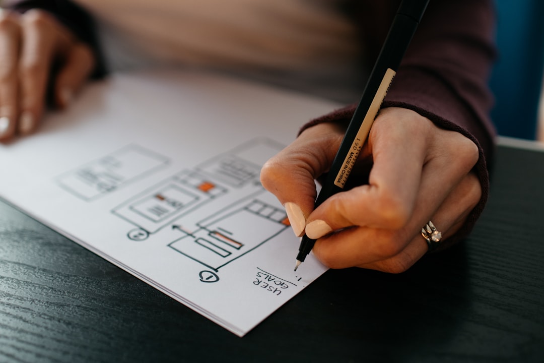 Designer drawing a landing page wireframe on paper — UX Work by picjumbo.com on Unsplash