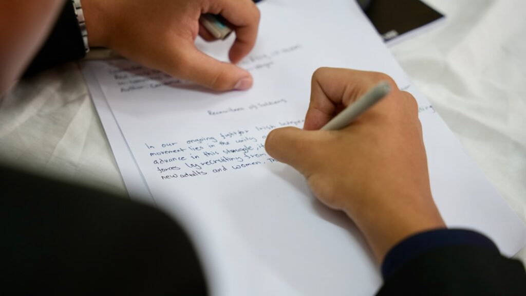 Close-up of a person writing copy notes by hand on paper, crafting persuasive messaging.